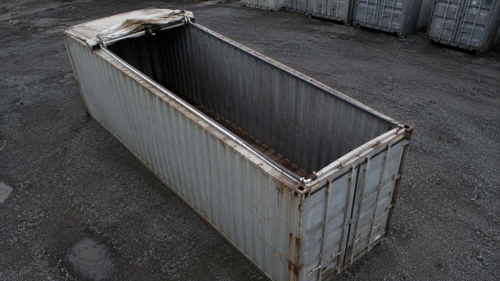 Åben open top-container uden tag, klar til kranlæsning på industrigrund