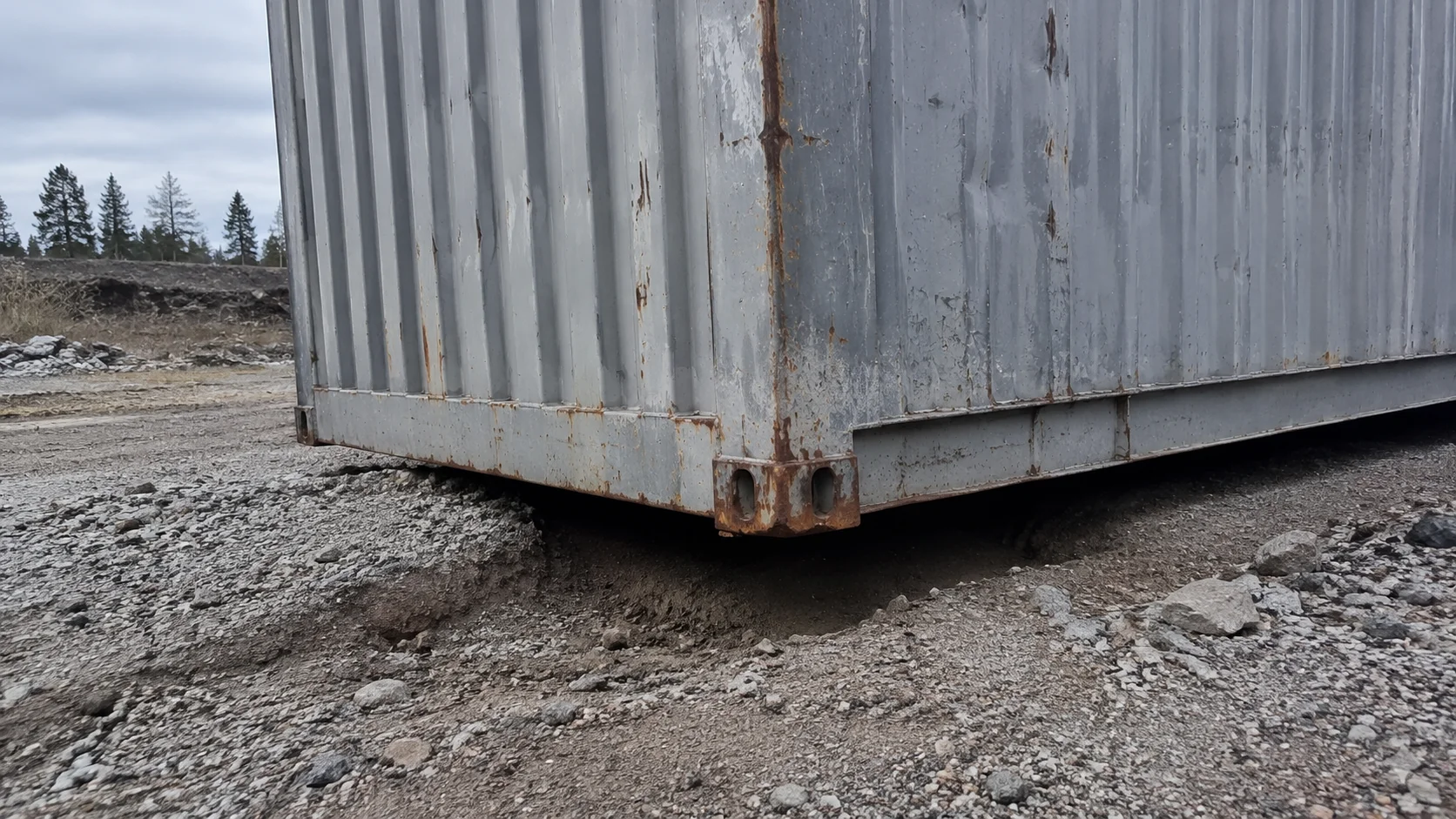 Container placeret skævt på et ujævnt underlag med synlig spalte under det ene hjørne