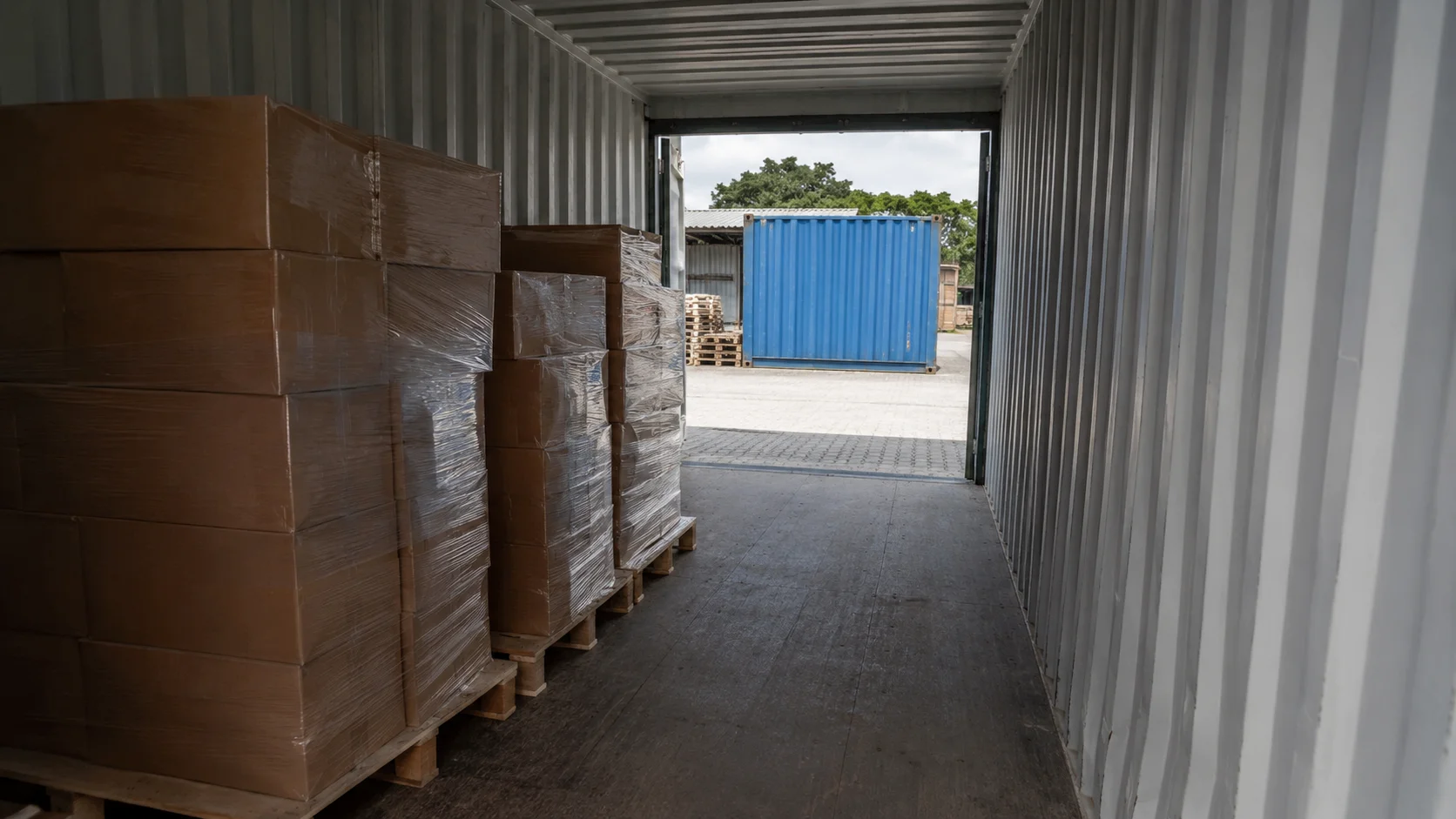 Palleopdelte flyttekasser stablet på afstand af gulvet inde i en opbevaringscontainer