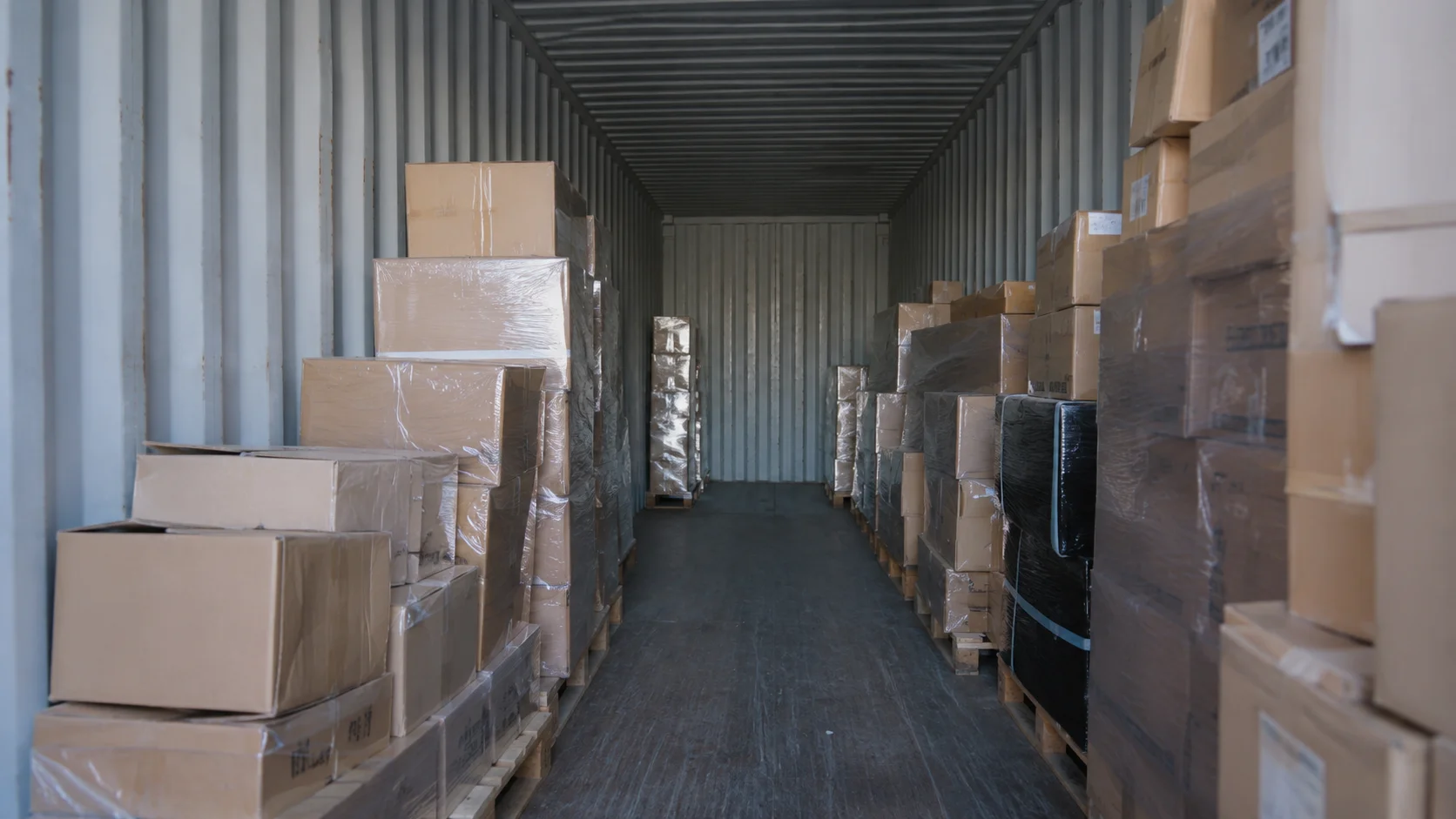 Flyttekasser og EUR-paller stablet inde i en åben 20 fods container