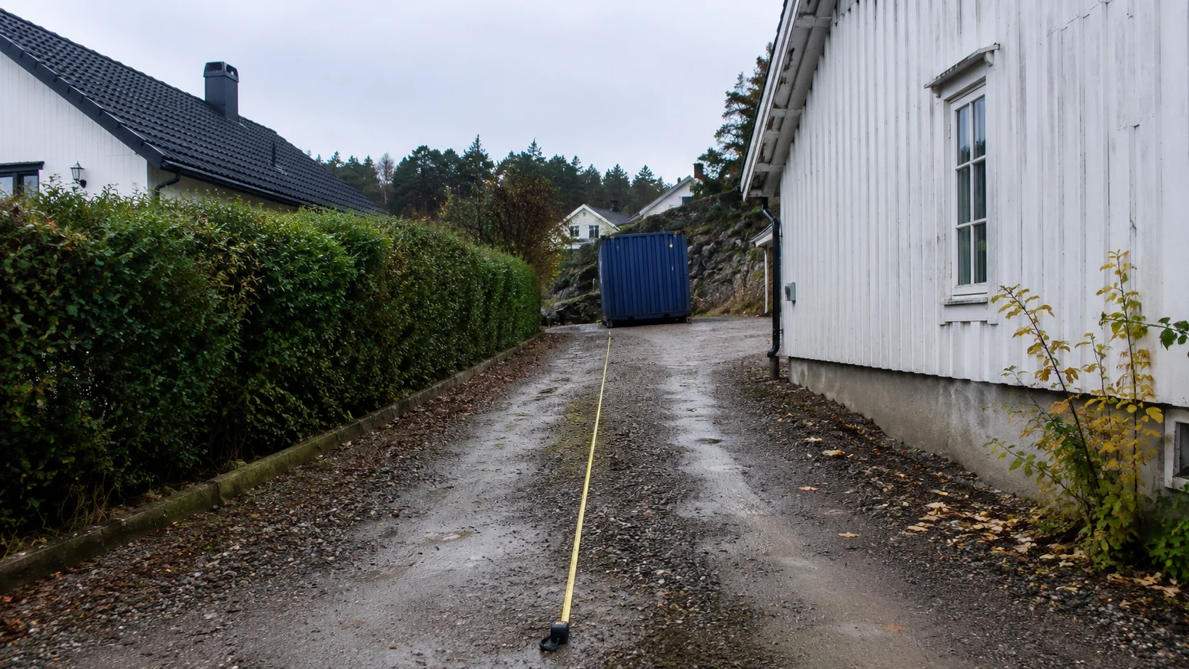 Indkørsel til en villagrund med målebånd og fri passage markeret op til en container klar til levering